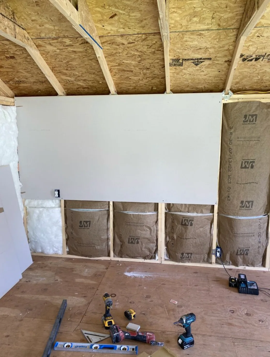 Drywall installation in progress with exposed framing and wall insulation