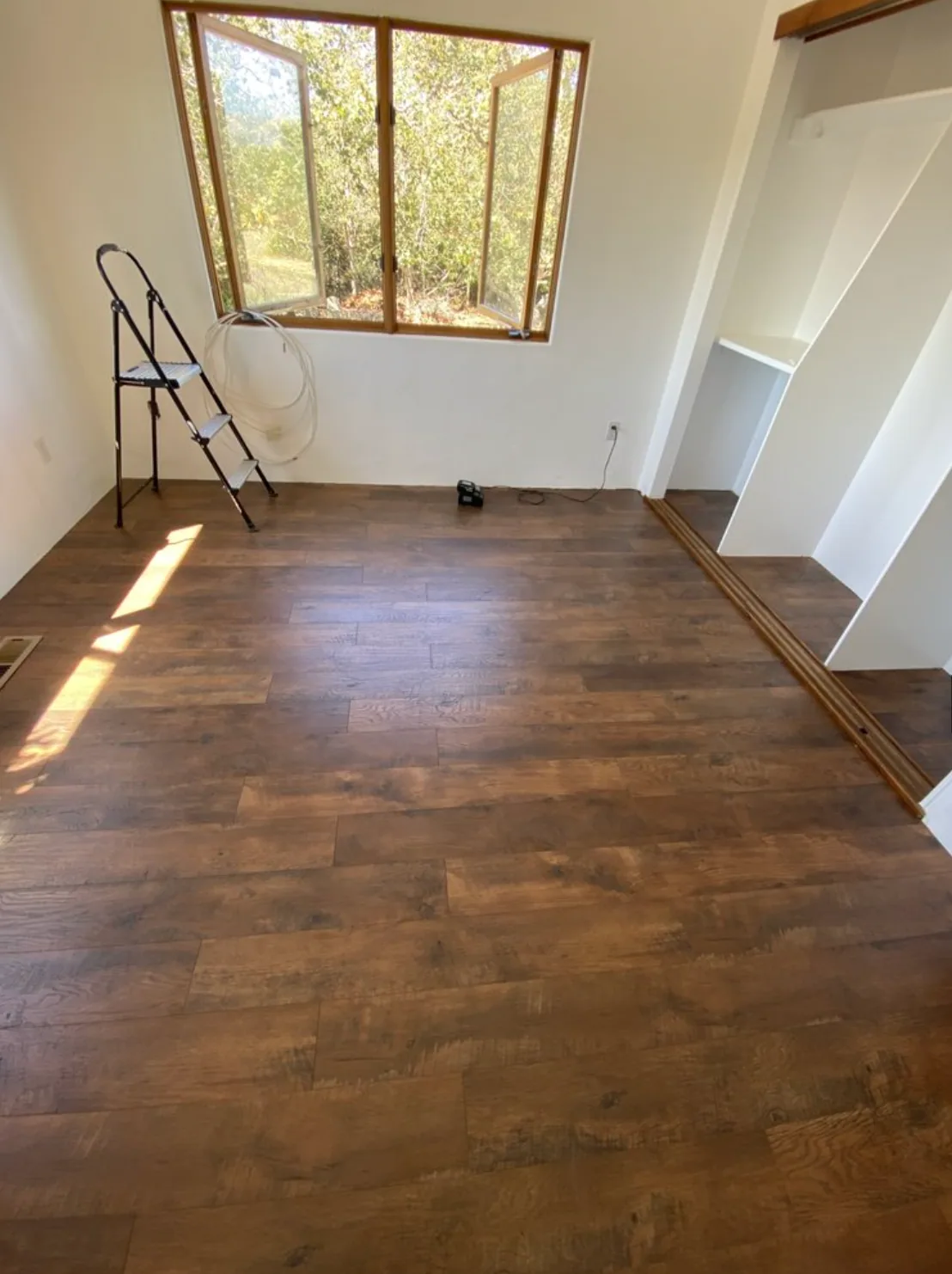 Room with wood-look flooring, freshly finished walls, and built-in shelving
